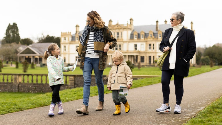 A family dressed for winter walk along a path with a house behind them